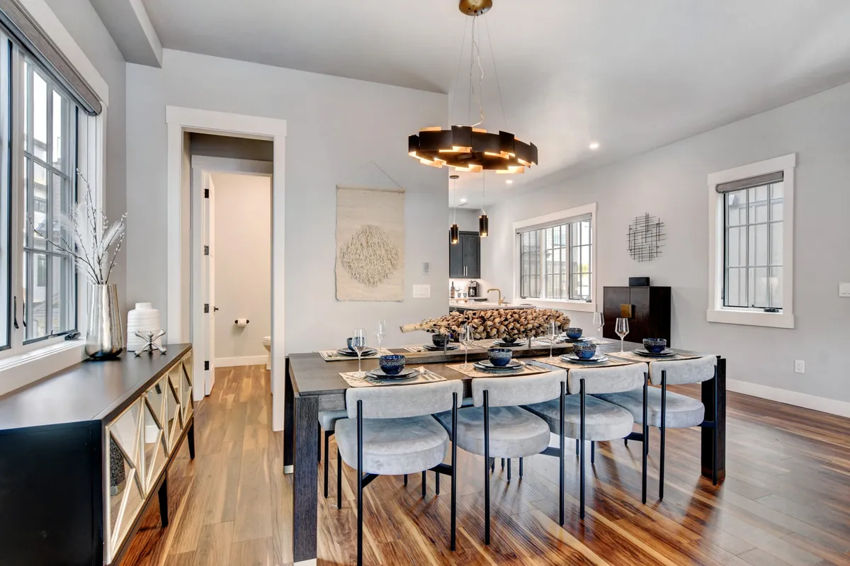A warm and welcoming dining area centered around a handcrafted wood table, illuminated by a statement chandelier. The scene is set for meaningful meals, with tasteful wall art and a sideboard enhancing the inviting ambiance.