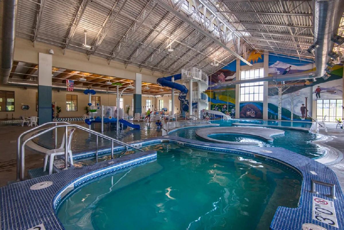 A lively indoor pool area with a colorful water slide, play structures, and a joyful family atmosphere. Children are enjoying water play, making this a vibrant family-friendly space for recreation and fun.