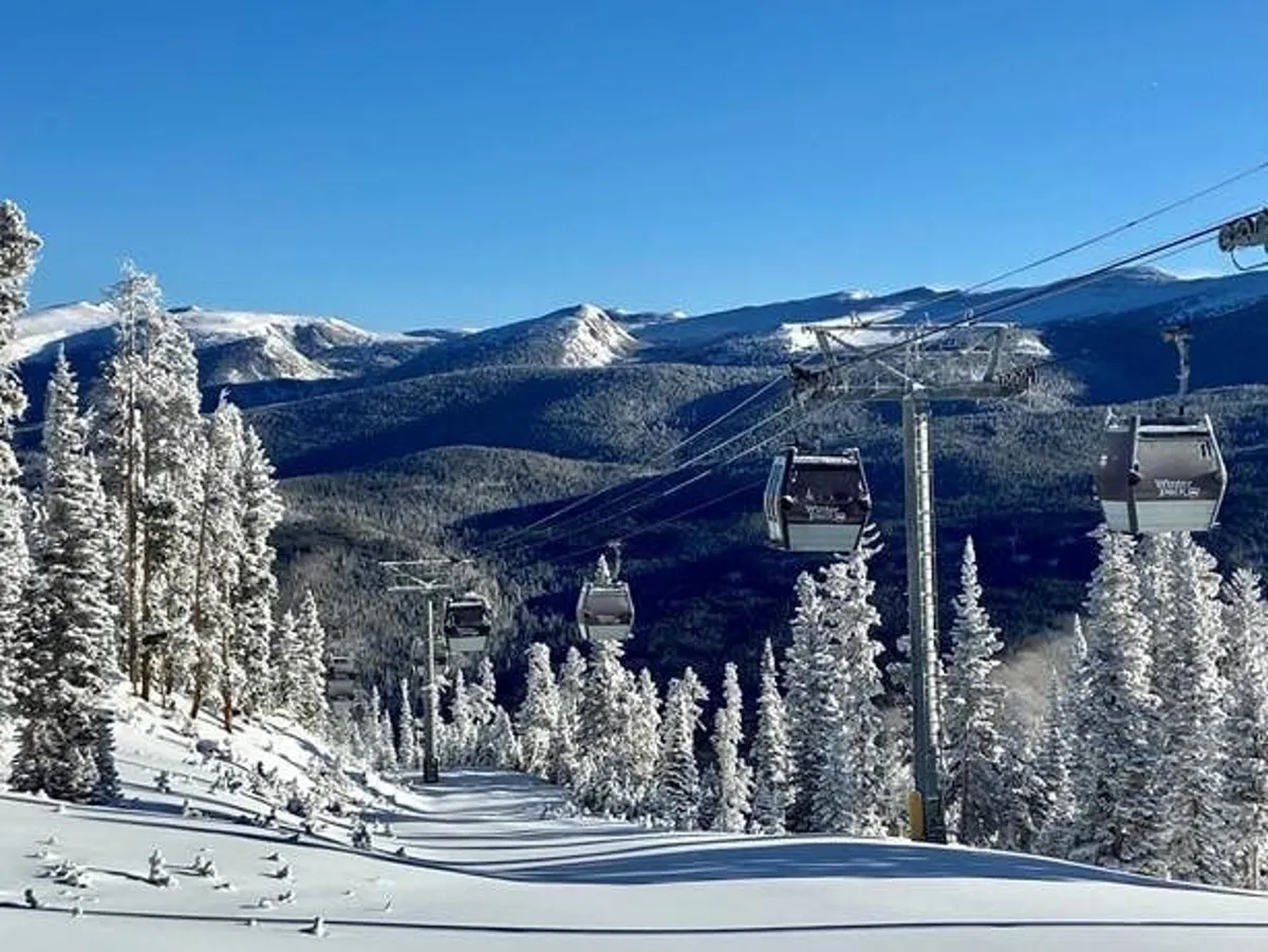 A dynamic winter landscape featuring a ski lift ascending snow-covered slopes, bordered by pine trees with distant mountains framing the scene. The area is lively, suggesting activity and adventure, with clear references to winter sports such as skiing, snowboarding, and snowshoeing.