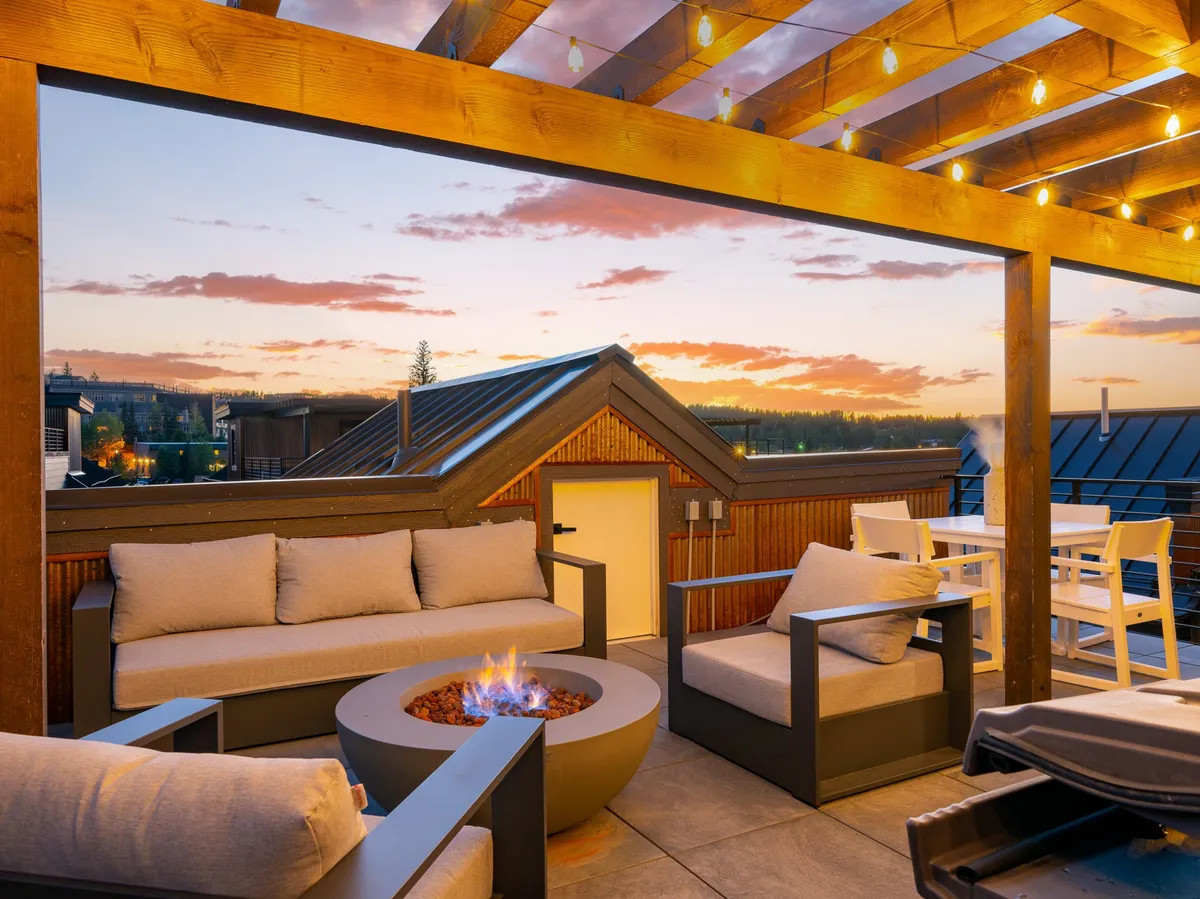 A tranquil exterior seating area around a glowing fire pit, with string lights overhead and a panoramic sunset view. The arrangement is ideal for evening gatherings, storytelling, and stargazing, encapsulating the spirit of family connection outside the home.