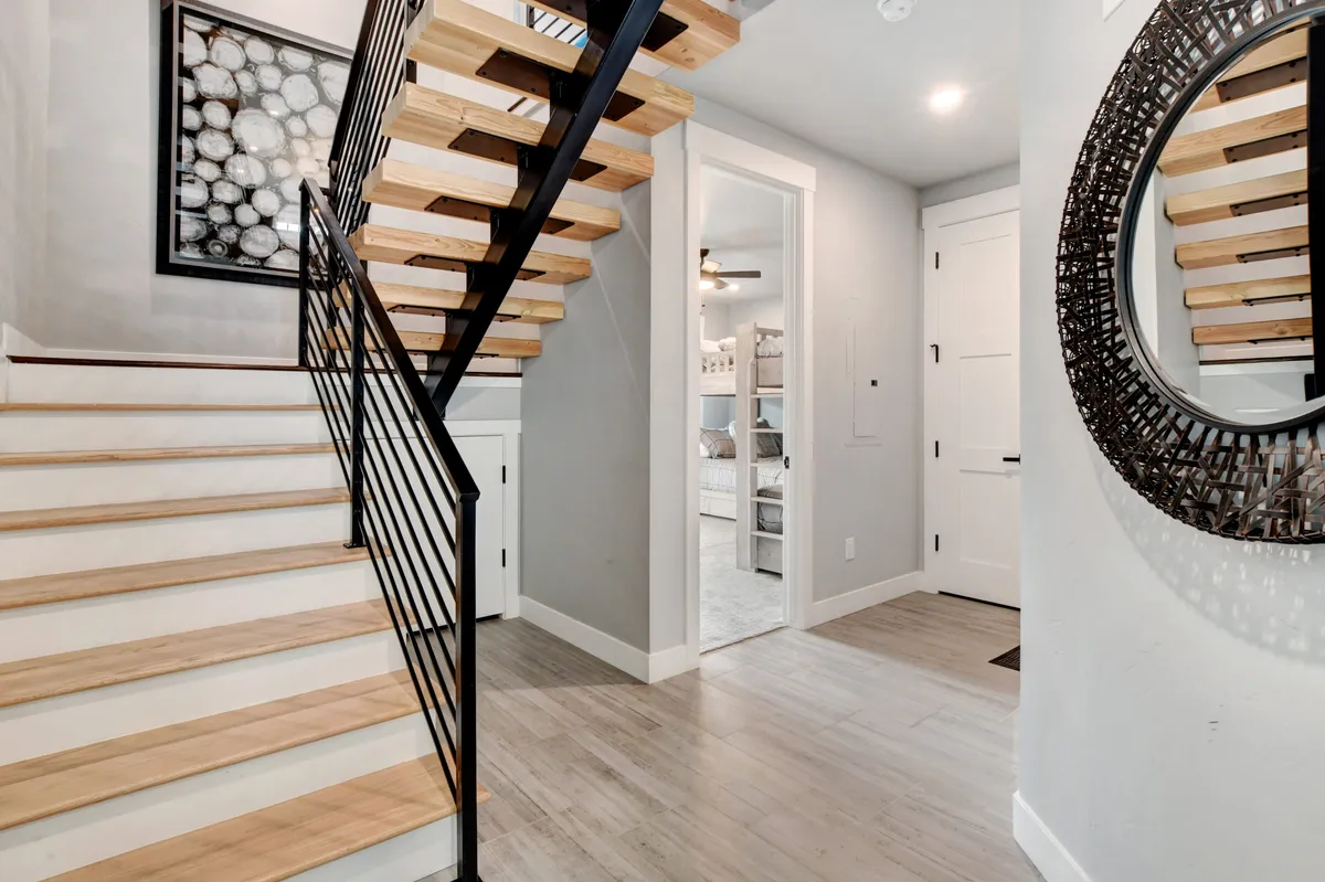 This image features an open staircase, decorative mirror, and eye-catching wall art, creating an inviting, modern ambiance. Its crisp lines and uncluttered feel contribute to an impression of freshness and order.