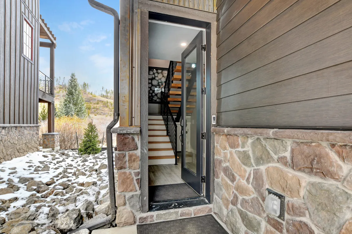 This image captures the home's entrance door, a stone wall, and a staircase leading upward. The welcoming entryway exudes warmth and cleanliness, with a tidy and organized presentation that suggests a well-maintained, orderly environment.